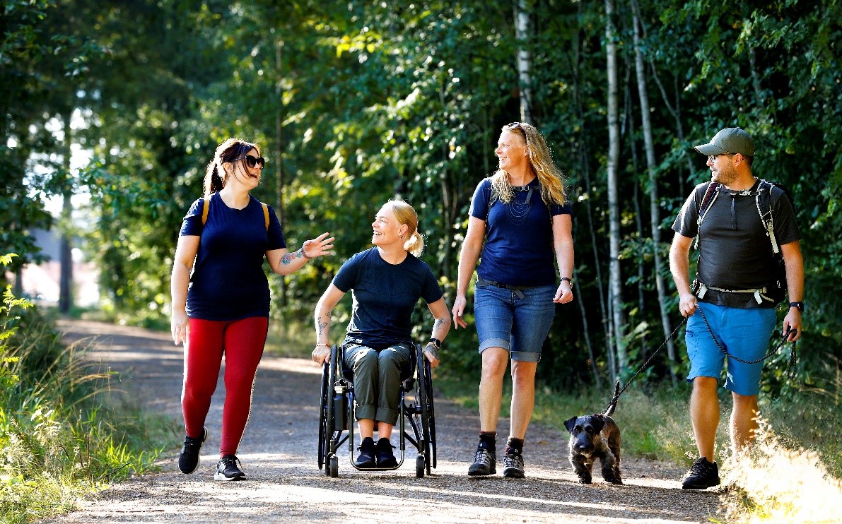 Fyra personer och en hund på en skogsväg.